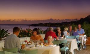 a group of people eating at a restaurant with the ocean in the background at Hotel Gran Rey in Valle Gran Rey
