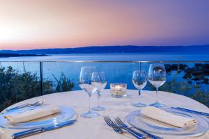 a table with wine glasses and napkins and a view of the ocean at Hotel Dei Pini in Alghero