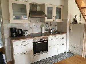 a kitchen with white cabinets and a sink and a refrigerator at Hafenambiente in Husum