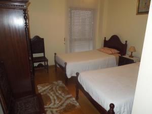 Un dormitorio con dos camas y una silla y una ventana. en Borges Pimentel Apartment, en Ponta Delgada