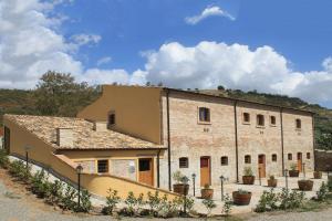 um velho edifício de tijolos com vasos de plantas em frente em La Peschiera B&B em San Lorenzo del Vallo