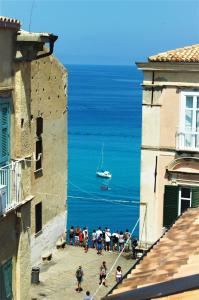 Un groupe de personnes marchant entre deux bâtiments avec un bateau dans l'océan dans l'établissement B&B The Tower, à Tropea