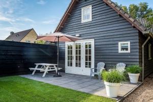 a patio with an umbrella and a table and chairs at Slapen aan de Bosweg in Zoutelande