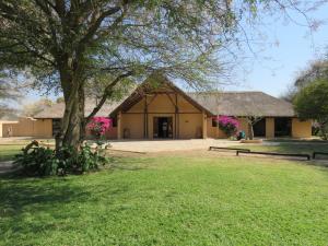 Kayova River Lodge في Ndiyona: مبنى فيه شجره وسط الميدان