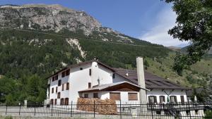 a white building with a mountain in the background at Hotel Roburent in Argentera