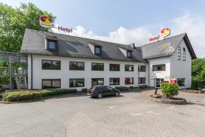 ein Hotel mit einem Auto auf einem Parkplatz in der Unterkunft Serways Hotel Heiligenroth in Montabaur