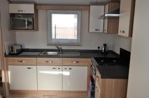 a small kitchen with white cabinets and a sink at West Loch Shores in Tarbert