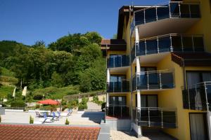 ein Gebäude mit Balkonen, Tischen und Stühlen in der Unterkunft Residence am Weinberg / Travellers Hotelbetriebs GmbH in Sasbachwalden