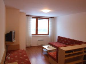 salon z czerwoną kanapą i oknem w obiekcie Apartman Ašek w mieście Ramzová