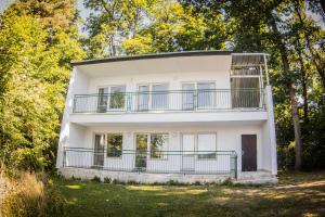 een wit huis met een balkon en bomen bij Yacht Club Bezdrev in Hluboká nad Vltavou