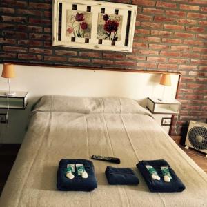 Una cama con dos zapatillas y un mando a distancia. en La Posada, en Villa Ventana