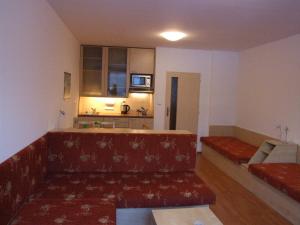 蘭佐瓦的住宿－Apartman Ašek，一间带红色沙发的客厅和一间厨房