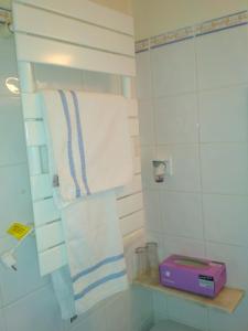 uma casa de banho com toalhas brancas e uma caixa roxa numa prateleira em Morbey's Chalet em Sintra