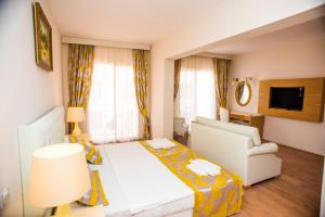 una camera d'albergo con letto, divano e TV di Ladonia Hotels Del Mare a Gümbet