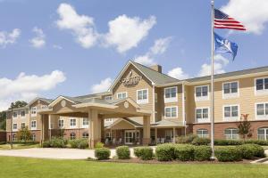 Pineville的住宿－派恩維爾鄉村套房酒店，挂着美国国旗的酒店前方的图片