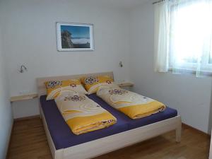 シュルンスにあるFerienwohnung Bergblickのベッドルーム1室(黄色と白の枕付きのベッド1台付)