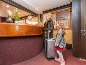 Une femme et une petite fille avec une valise dans un bar dans l'établissement Résidence Odalys Chanteneige Croisette, aux Menuires