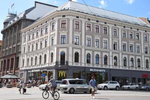 a large white building on a city street with people on bikes at Liberty Airy in Rīga
