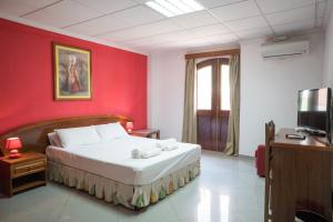 um quarto com uma cama com uma parede vermelha em Royal Mindelo Suite em Mindelo