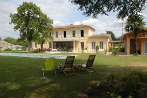 un patio con sillas, una casa y una piscina en Les Ambèles, en Saint-Magne-de-Castillon