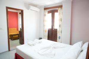 Cama blanca en habitación con ventana en Royal Mindelo Suite, en Mindelo