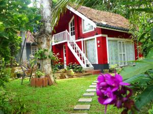a red house with a tree and a purple flower at Paradise Cottage Kandy in Kandy