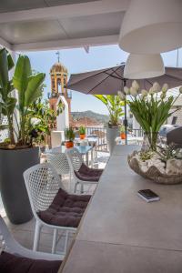 un balcone con tavolo, sedie e torre dell'orologio. di Almijara Residence a Cómpeta