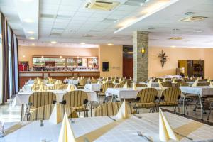 a banquet hall with white tables and chairs at Duna Hotel in Paks