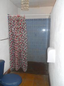 a bathroom with a shower curtain with a toilet at Beach Hostal Oasis in Las Peñitas