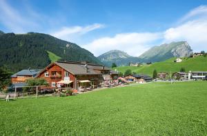 a village with a green field and mountains in the background at Schrannenhof in Schoppernau