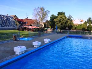 ein Pool aus blauem Wasser mit zwei weißen Tischen darin in der Unterkunft Hotel ROSE Břeclav in Břeclav