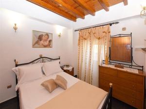 a bedroom with a bed with a dresser and a television at Akadia Syros in Ermoupoli