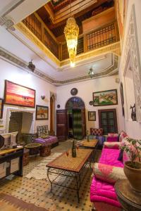 sala de estar con muebles de color rosa y lámpara de araña. en Riad Anass Al Ouali, en Fez