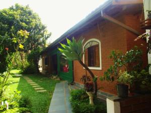 a small brick house with a palm tree in the yard at Pousada Nasa in São Bento do Sapucaí +32 photos