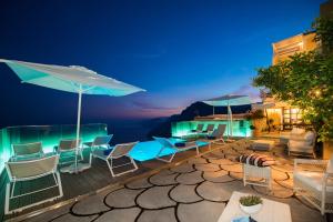 a deck with chairs and umbrellas at night at Villa Degli Dei Luxury House in Positano