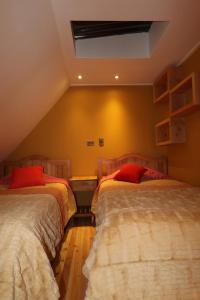 a bedroom with two beds with red pillows at Hostal Corvatsch in San Pedro de Atacama