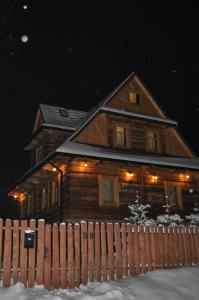 uma casa de madeira com uma cerca na neve em Legenda Tatr em Zakopane