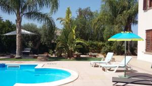 een zwembad met 2 stoelen en een parasol bij B&B Castellazzo in Paceco