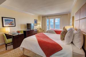 a hotel room with two beds and a desk and a television at Sea View Hotel in Miami Beach