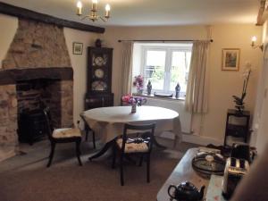 a living room with a table and a stone fireplace at Deepaller Farm in Tiverton