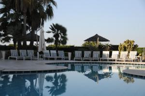una piscina con sillas y sombrillas junto a un complejo en Sunshine Club Hotel Centro Benessere, en Ricadi