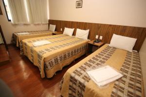 a hotel room with two beds in a room at Hotel Presidente Ipatinga in Ipatinga