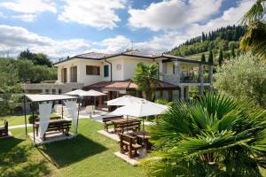 una casa con giardino attrezzato con tavoli e ombrelloni di Casaliva Relais a Bardolino