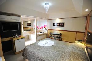 a bedroom with a bed and a television and a table at Hotel Premium Plaza in Muriaé