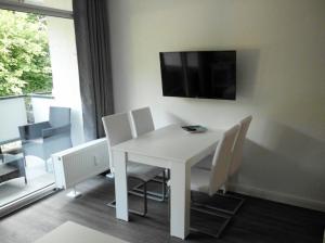 a white dining room table with chairs and a tv on the wall at Apartment Regina in Möhnesee