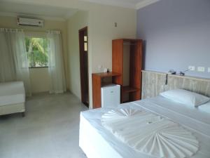 a bedroom with a white bed with an umbrella on it at Areia do Atlantico Hotel in Porto Seguro