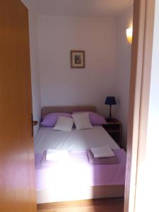a bedroom with a bed with purple sheets and pillows at Apartman Matić in Ston