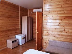 a room with wooden walls and a refrigerator and a bed at La Fontan in Sukhum