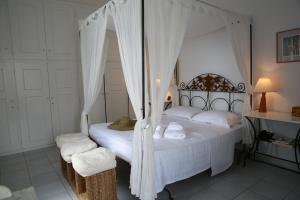 a bedroom with a canopy bed with white sheets at 360 Blue in Fira