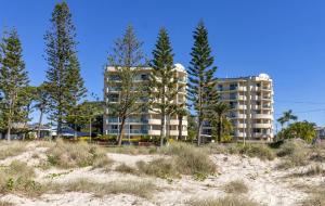 um edifício na praia com árvores em frente em Royal Pacific Resort em Gold Coast